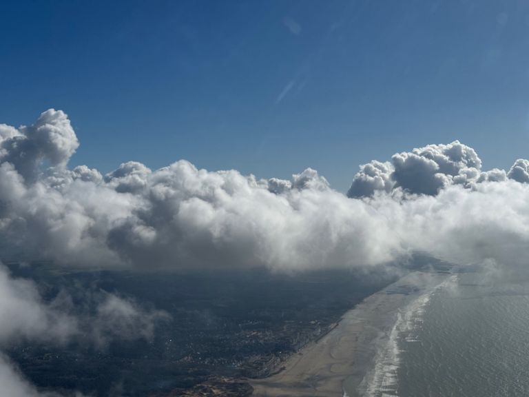 A cloudy sky with the Sussex coastline beneath